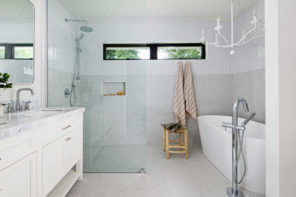 primary suite bathroom with deep soak tub, white chandelier and marble countertop